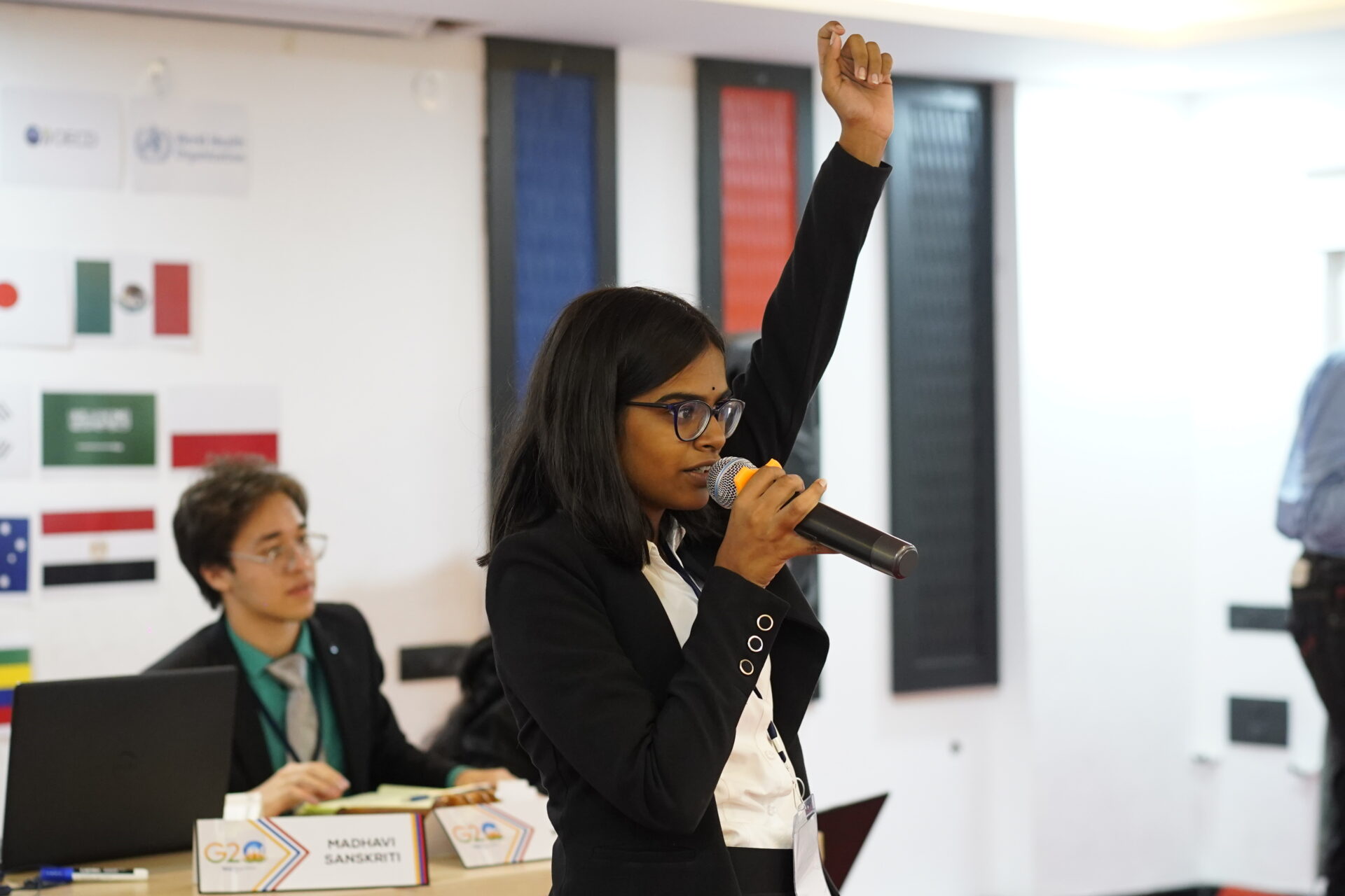 Premia Academy student delegate speaking at a Model UN or G20 simulation, raising her hand to debate.