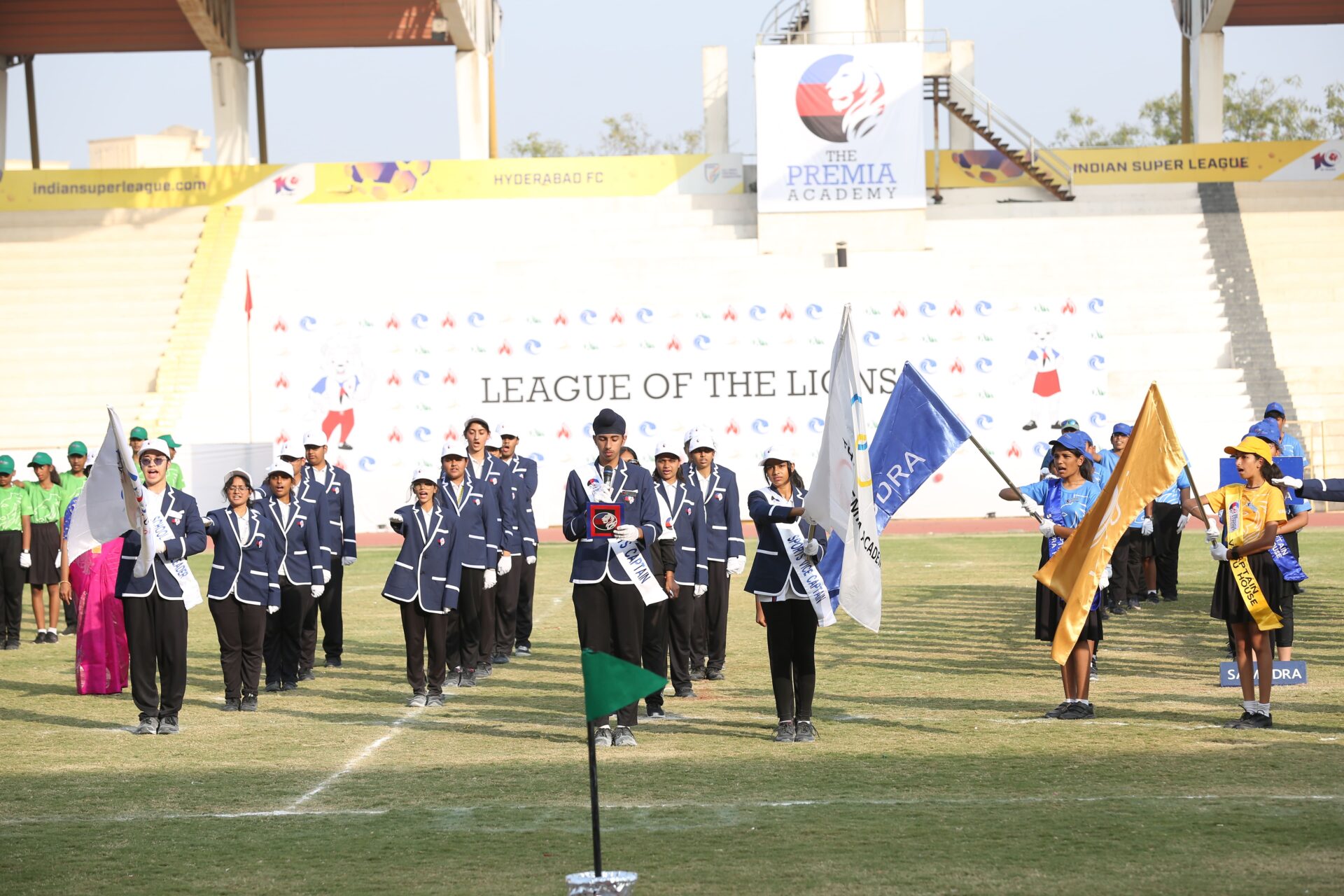 Premia Academy student leaders marching with house flags at the opening ceremony for the League of the Lions event.
