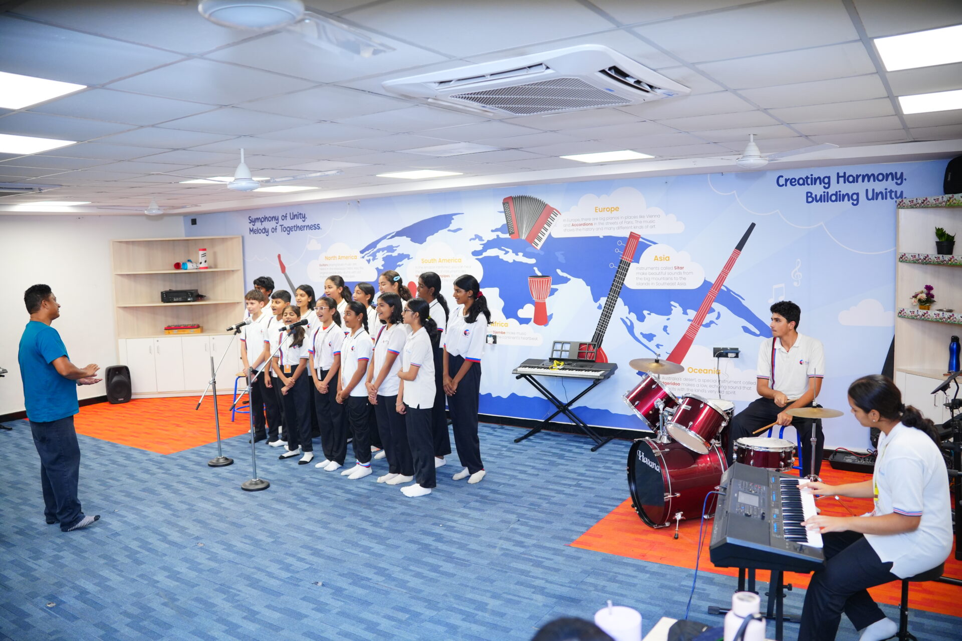 Premia Academy secondary students rehearsing in the music room choir, featuring drums and piano accompaniment.