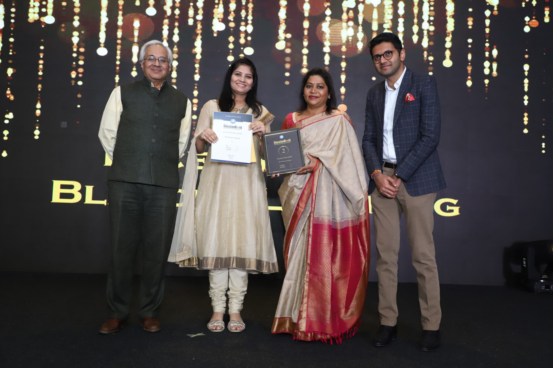 Premia Academy leaders receiving an EducationWorld award on stage for school achievements and excellence.