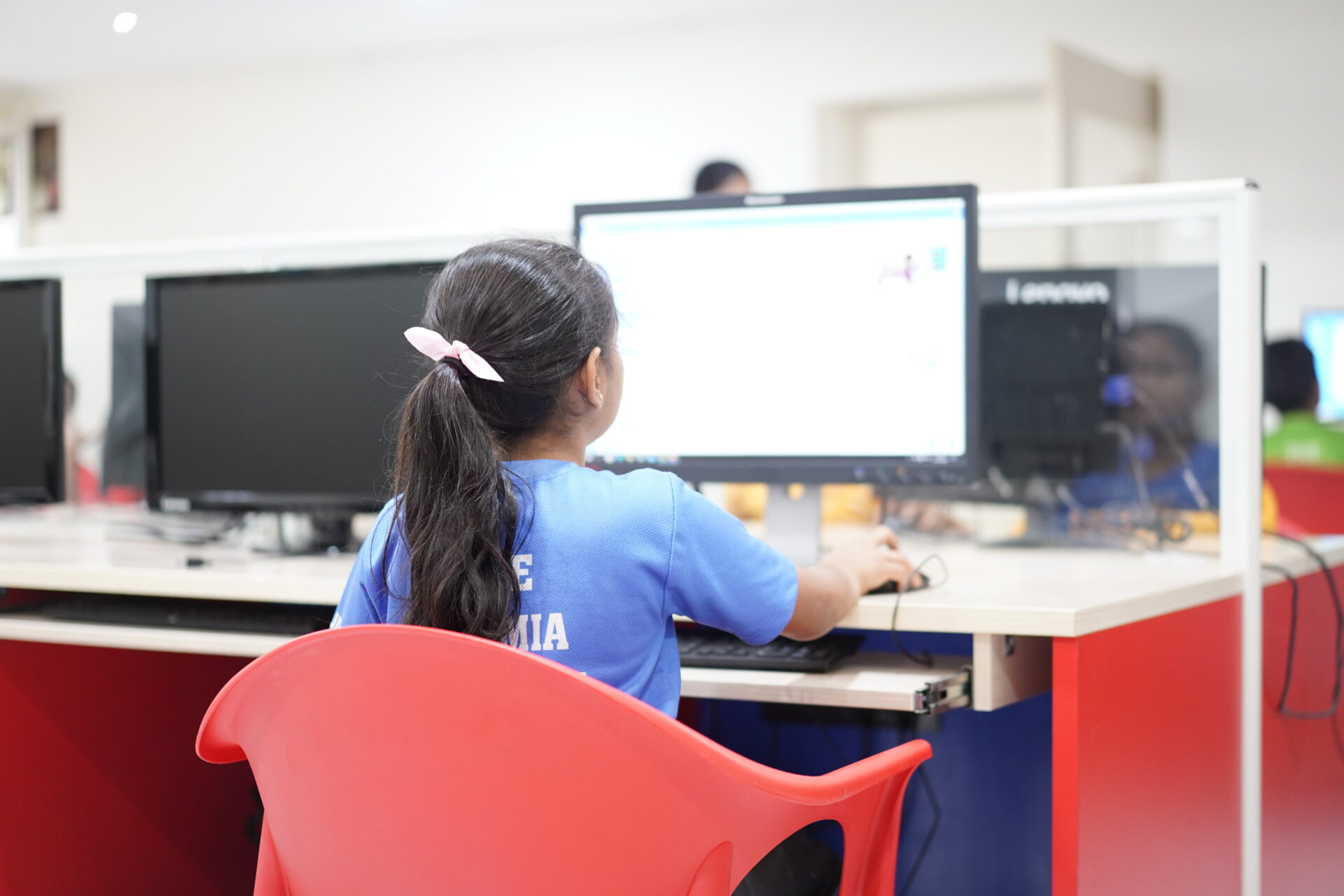 Premia Academy student working on a desktop computer in the IT lab during digital literacy class.