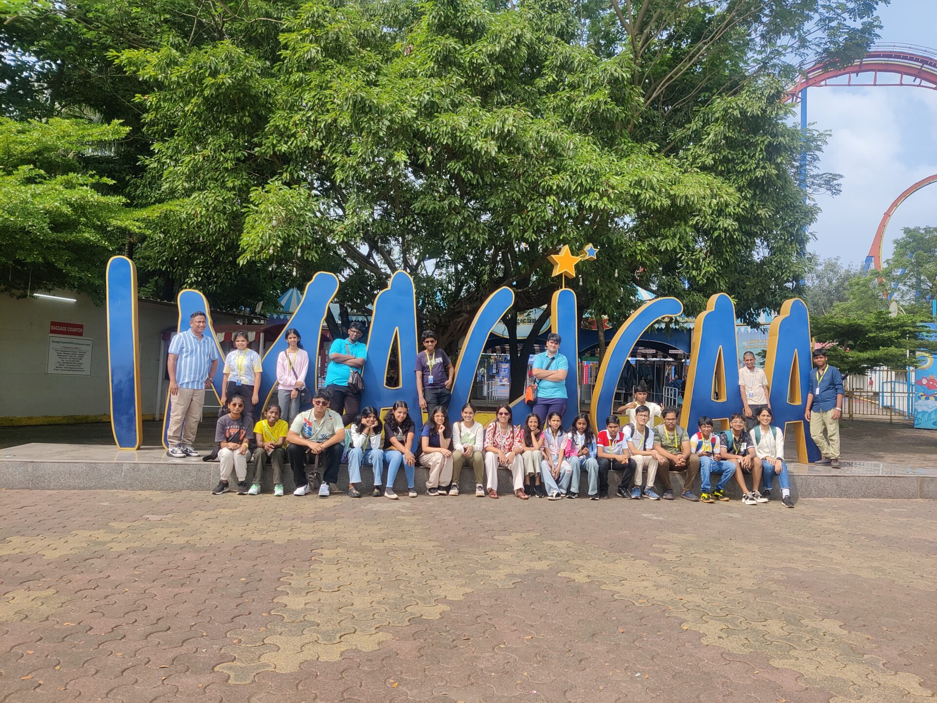 students and teachers posing in front of a large, blue 'IMAGICA' sign during a field trip