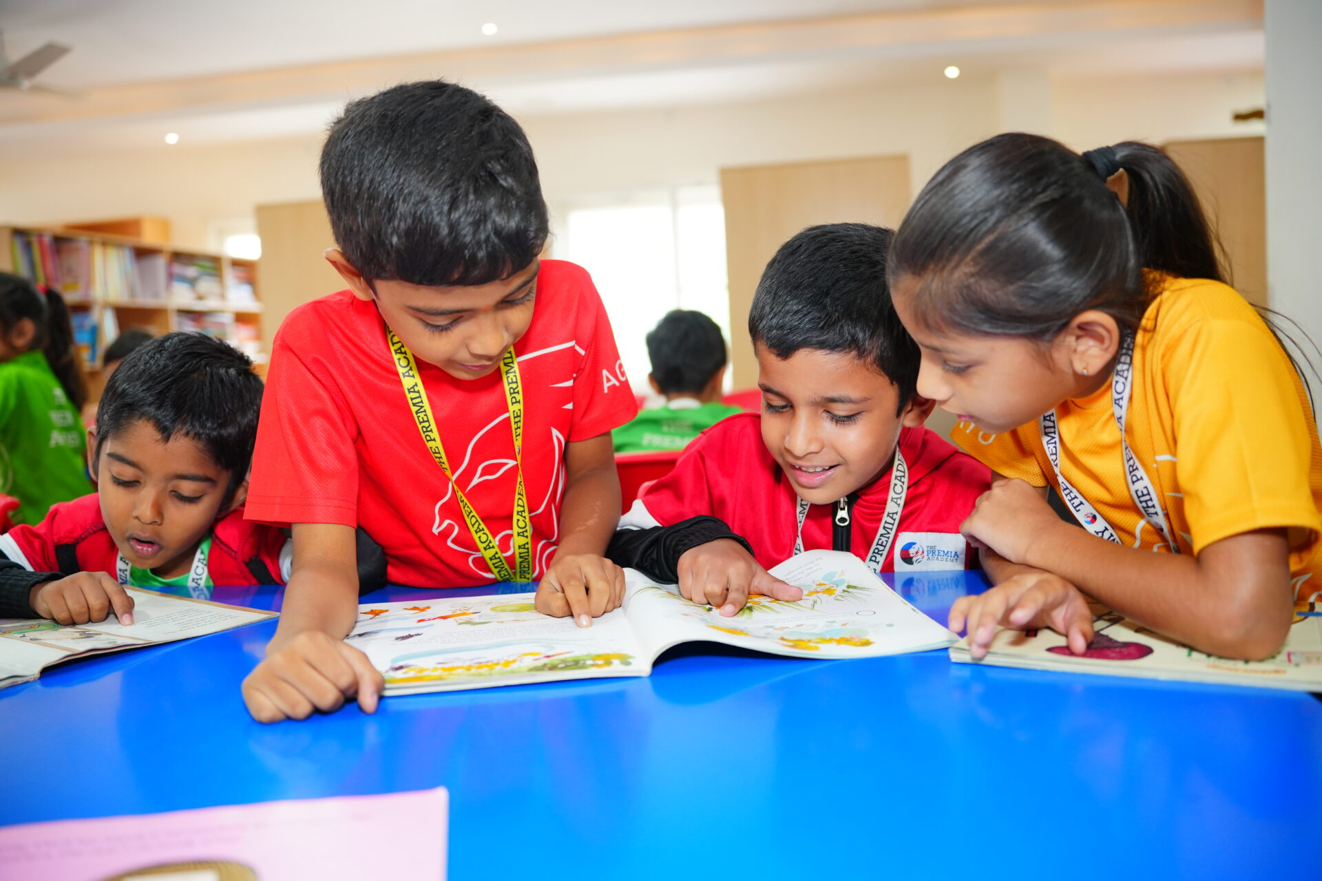 Premia Academy primary students engaged in collaborative reading and discussion, pointing to illustrations in a picture book.