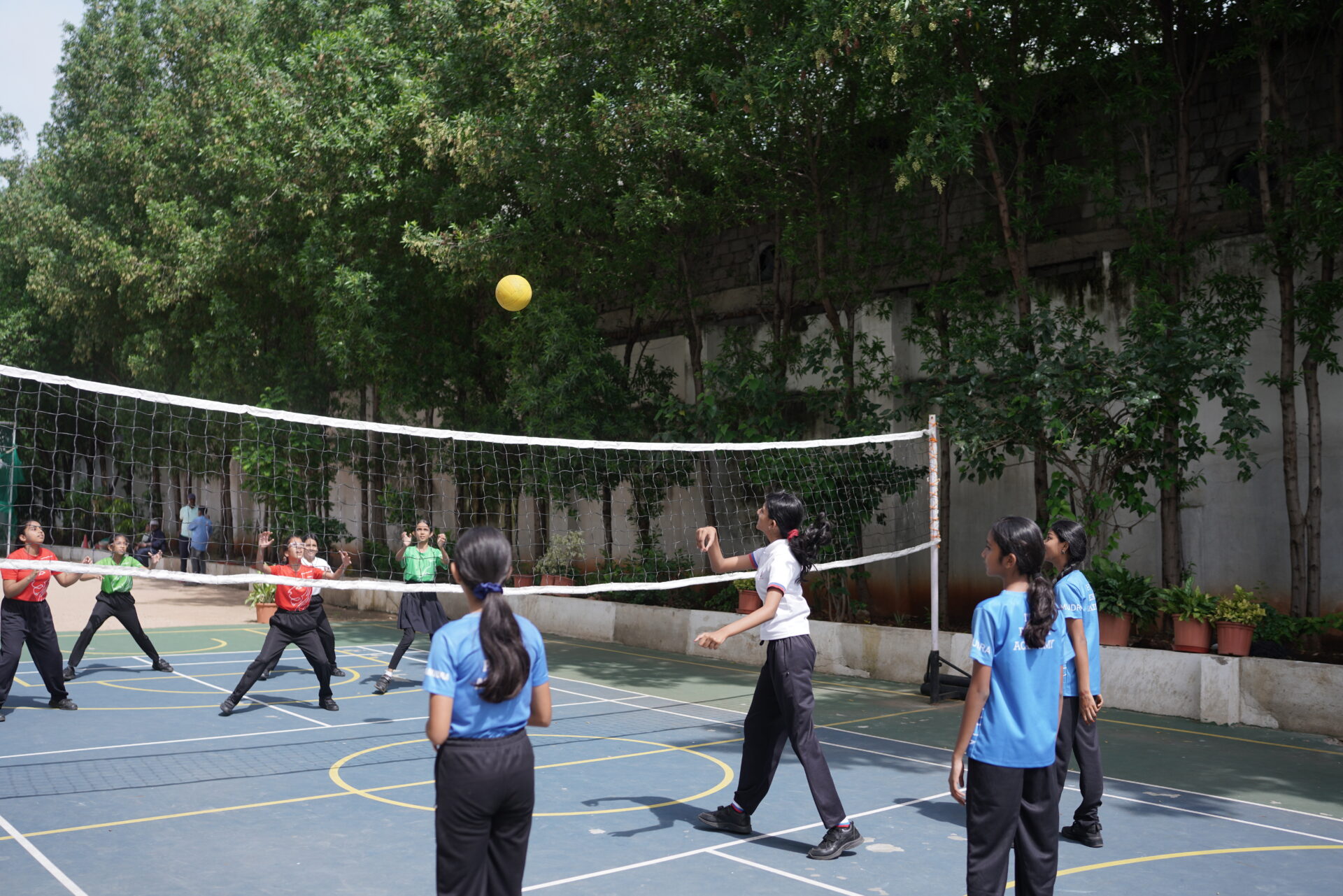 Secondary students playing volleyball on the outdoor school court during a physical education class