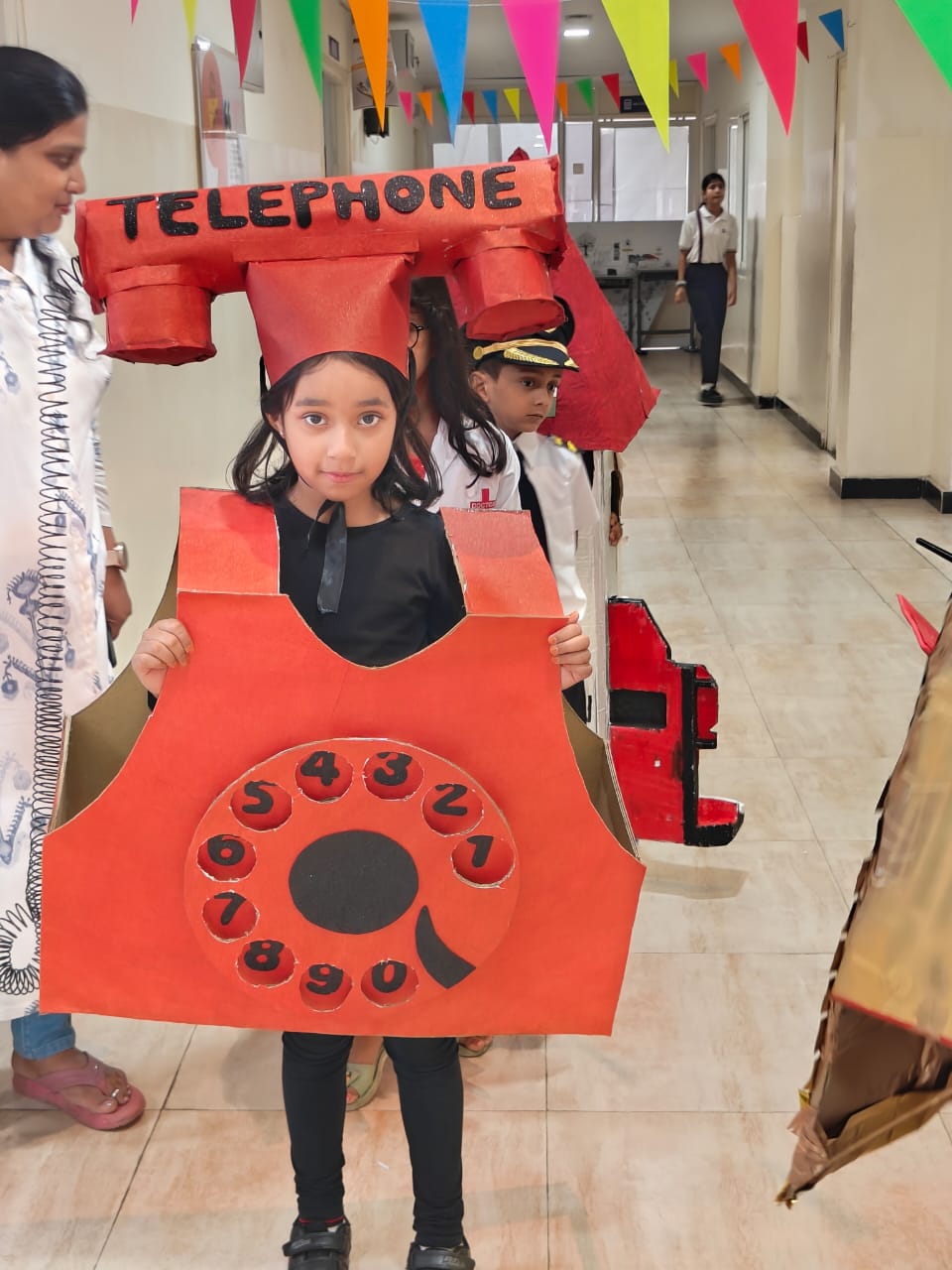 Primary student wearing a handmade rotary telephone costume in the school hallway during a costume event