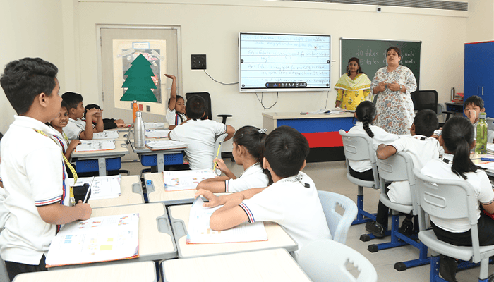 Premia Academy middle school students receiving instruction from two teachers in a modern classroom equipped with a smartboard.