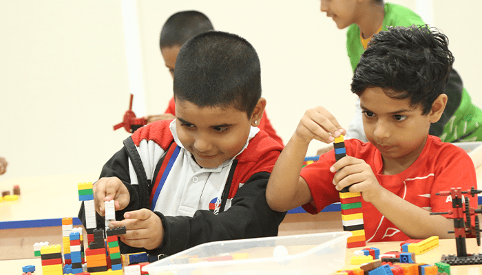 Primary students developing STEM skills through constructive play with colorful building blocks in a classroom.