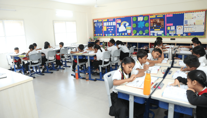 Premia Academy primary students engaged in individual work and focused learning at modern, modular desks in a spacious classroom.