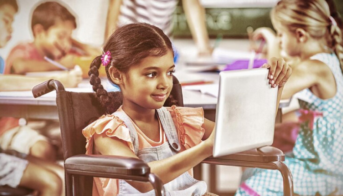 Premia Academy inclusive education: Student in a wheelchair engaging in digital learning using a tablet in the classroom.