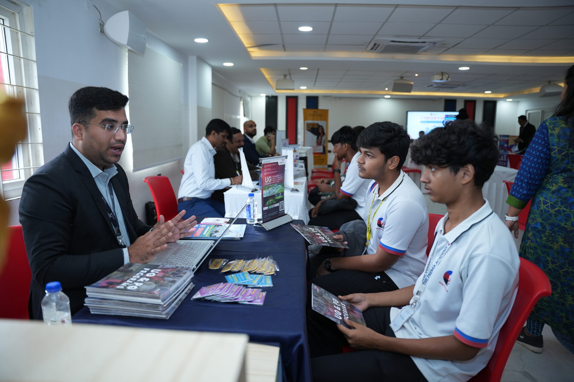 Students at a career fair, engaging with a representative at a table with brochures
