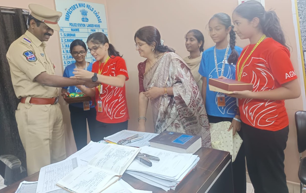 students and a teacher meet a police officer at a police station and present a gift